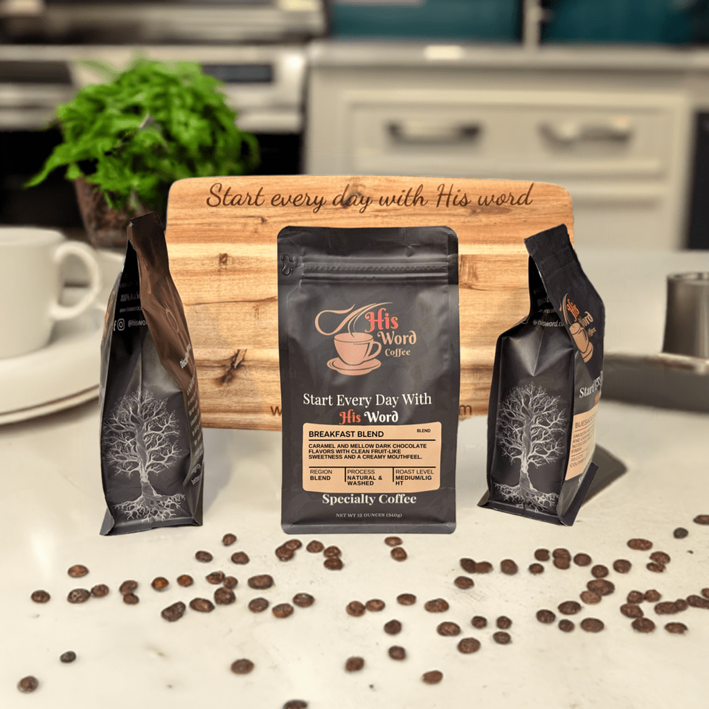 Breakfast Blend coffee bags on wooden table with scattered beans and His Word Coffee sign