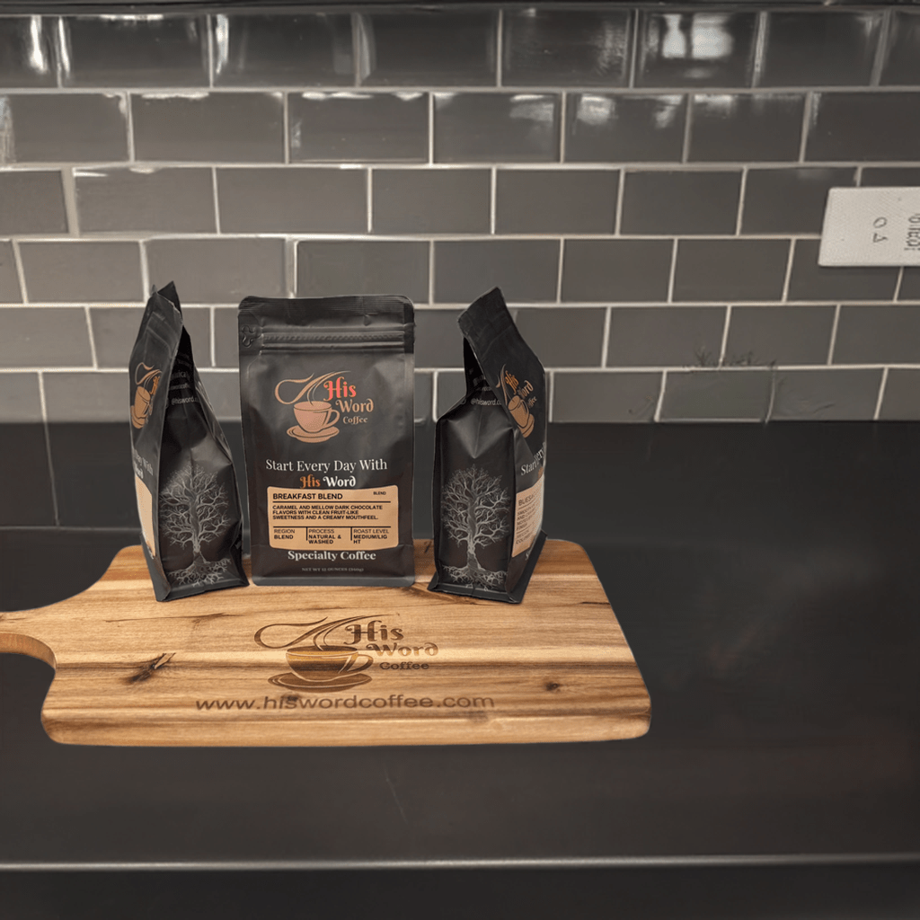 His Word Coffee Breakfast Blend bags on dark wood with brick background