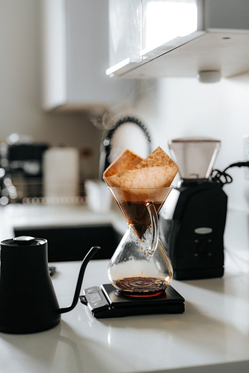 Chemex pour-over coffee setup with gooseneck kettle and grinder on white counter