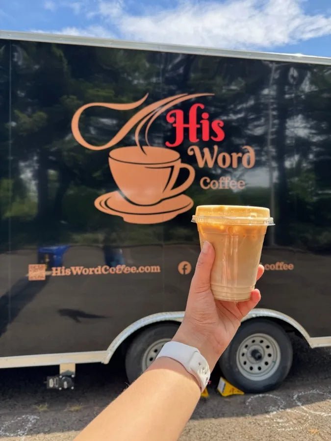 Fresh iced latte held up in front of the His Word Coffee trailer